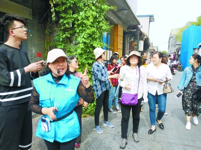 金牌导览员师文霞(左二)在杨梅竹斜街为游客讲解胡同故事.